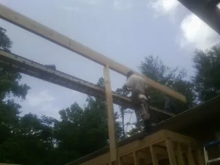 Carpenter setting a ridge beam over a new addition frame — Ice Dam Removal by Roofing Brothers in Polkville