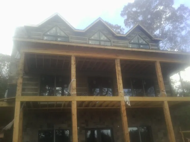 Dormers and porch framing on a large log home under construction — Roof Coating work by our crew in Polkville