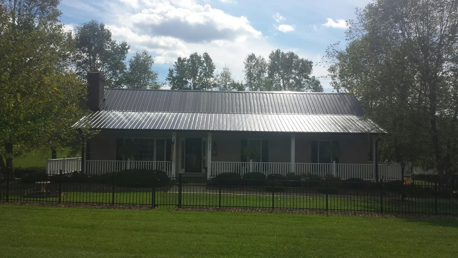 Gray metal roof on a brick ranch with a full width front porch — Gutter Guard Installation work by our crew in Polkville