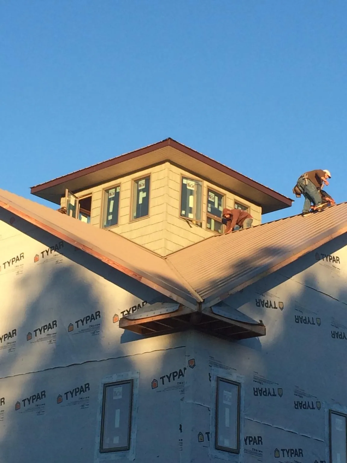 Roofers working around a rooftop cupola on a new metal roof at sunset — Roof Waterproofing in Polkville by Roofing Brothers